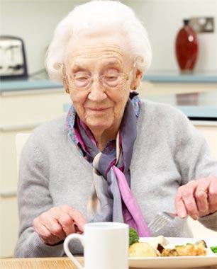Elderly woman eating a hot meal